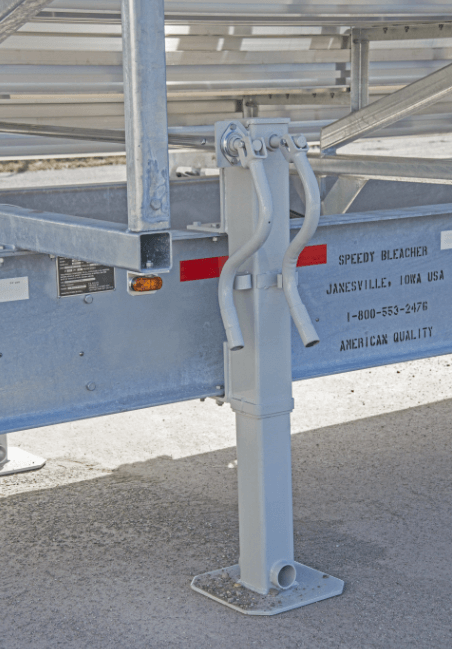 Hydraulic stabilizing jack on portable aluminum bleachers trailer, providing secure leveling and support during event setup.